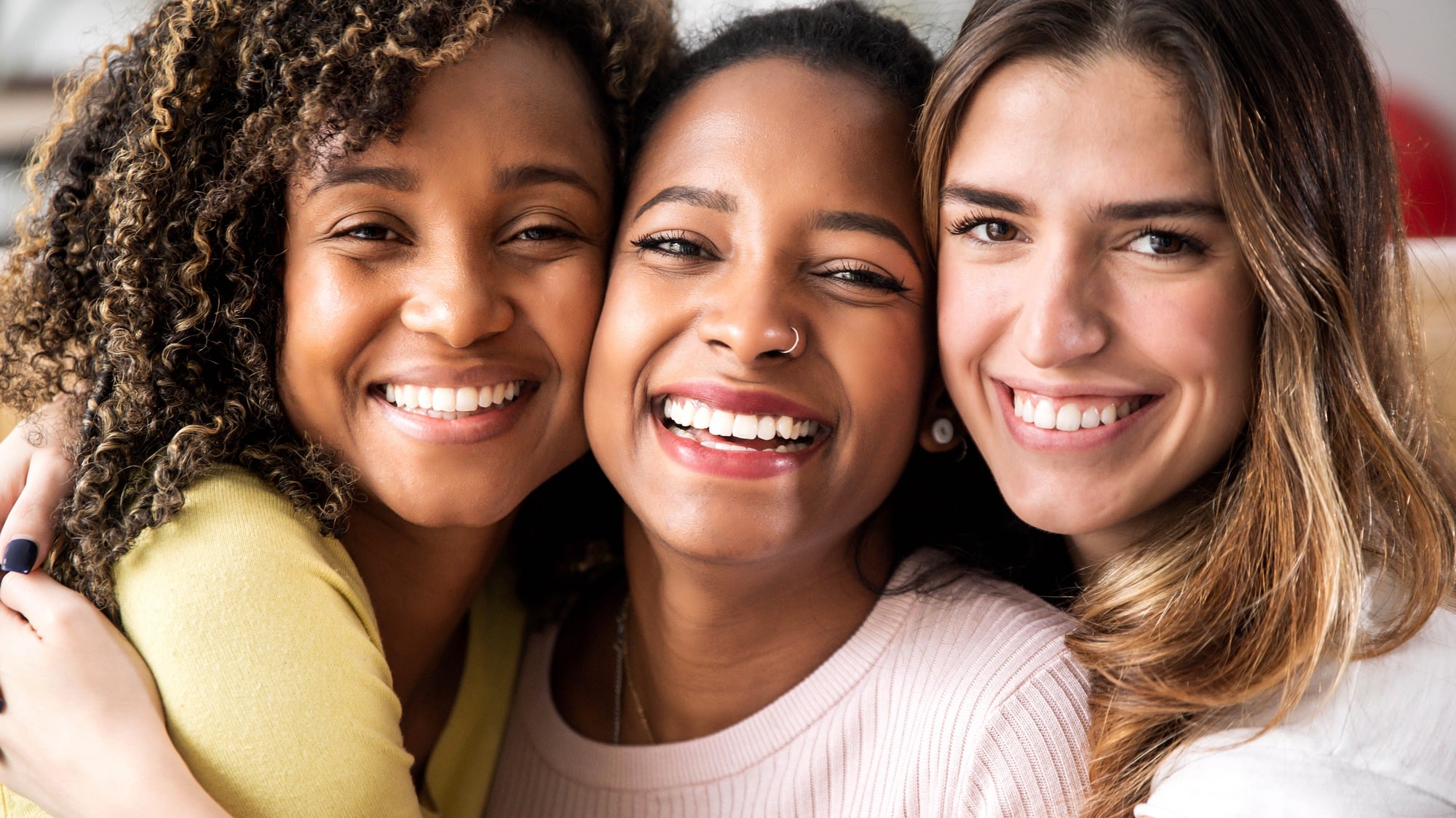 Three female friends with radiant smiles, symbolizing the confidence and happiness that dental implants from Mayfair Family Dentistry can restore.